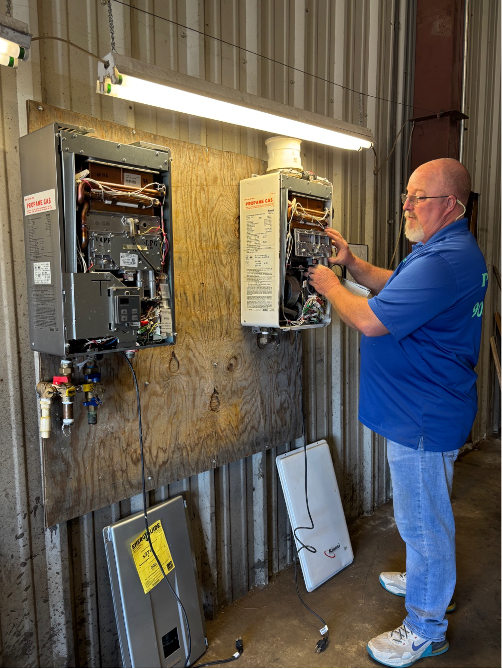A plumber installing a tankless water heater on a utility room wall.
