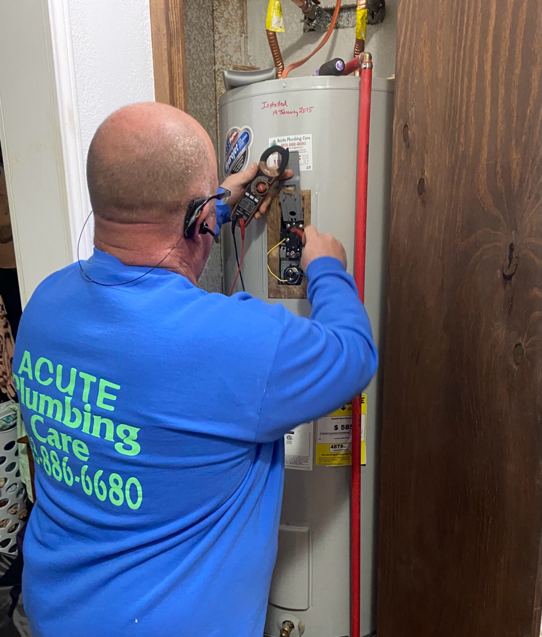 A technician servicing a residential water heater in a utility room.