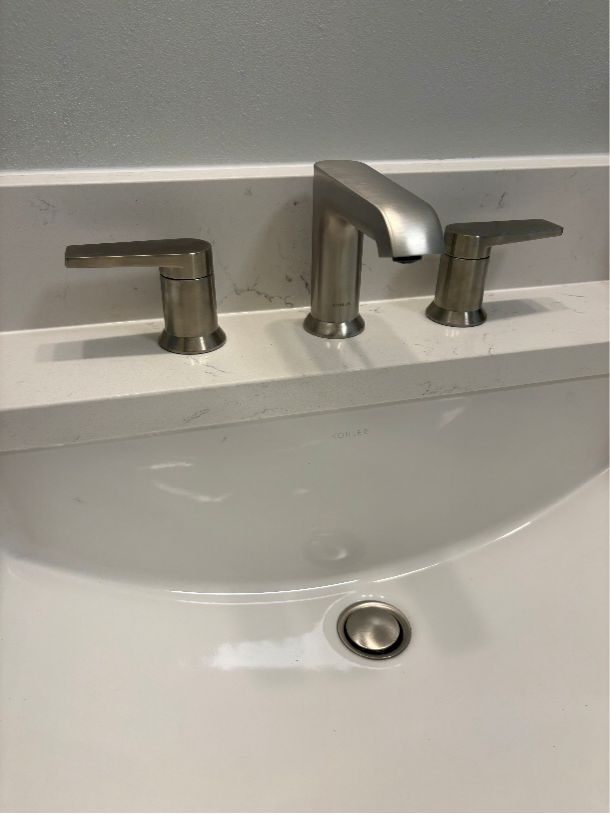 A close up of a modern bathroom faucet and sink, which may be leaking without visible signs