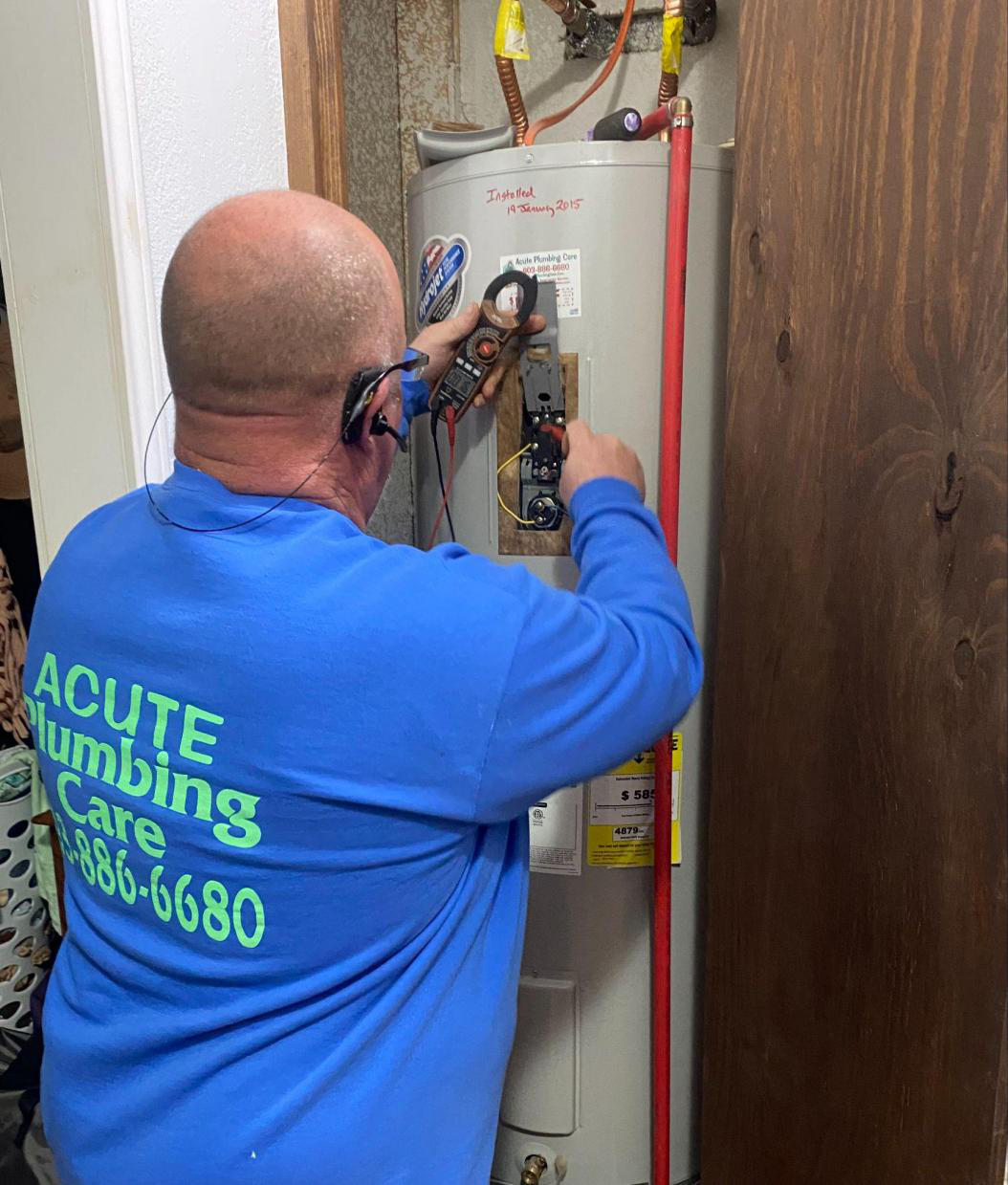 A professional plumber services a water heater.