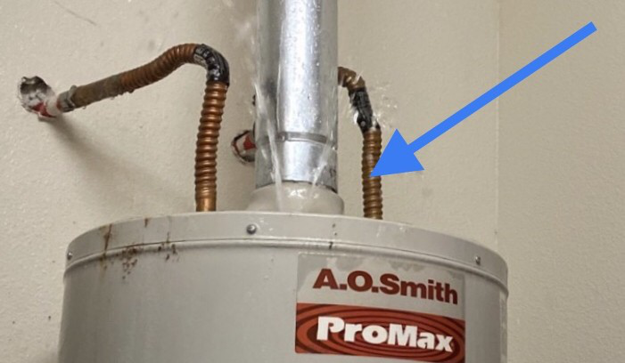 Close up of a corroded flexible pipe connection on an A.O. Smith ProMax water heater, indicating early signs of rust and wear.