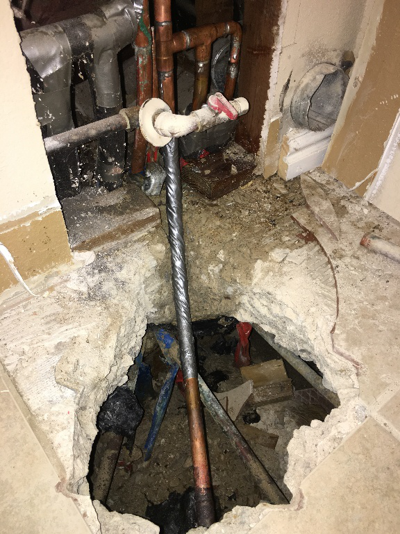 Exposed plumbing pipes and broken slab showing a completed slab leak repair
