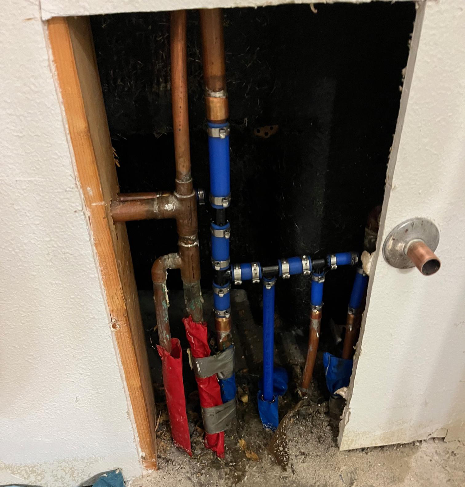 Exposed copper and PEX pipes with vent connections behind a wall