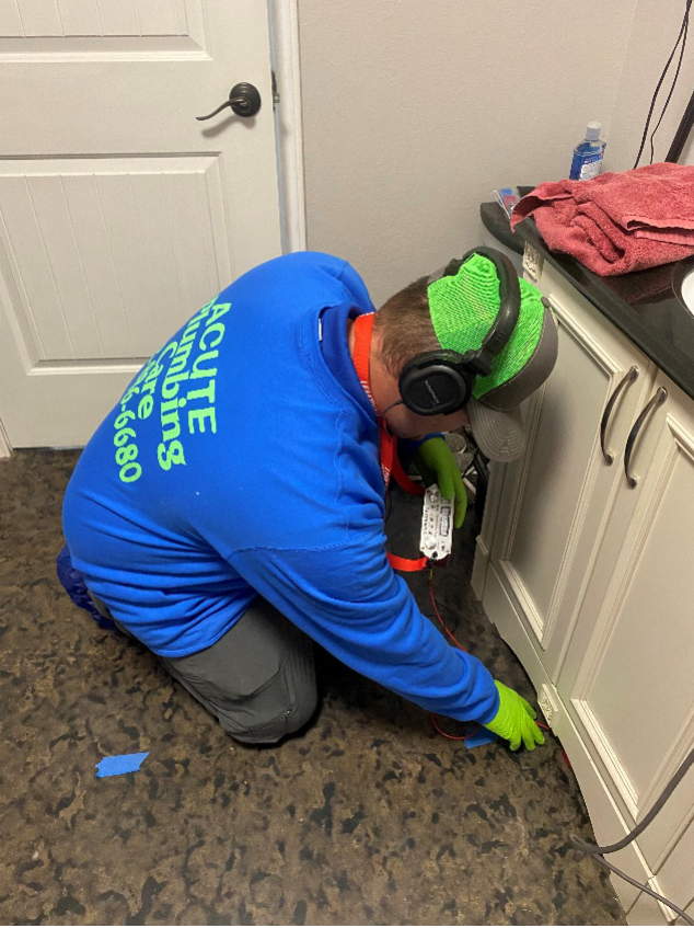 Licensed plumber using professional leak detection equipment inside a home