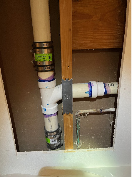 PVC vent and drain pipe installation exposed behind drywall