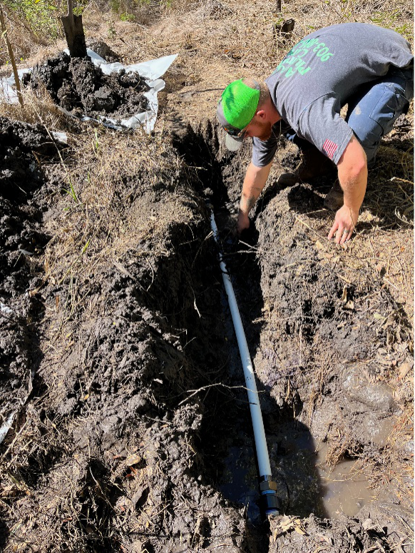Plumber working in muddy trench to replace an aging outdoor water line