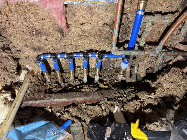Severe pipe corrosion with blue fittings and surrounding water damage